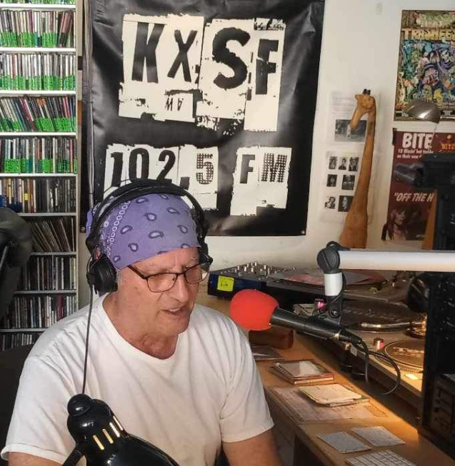 a man in a do-rag sits in a radio studio talking on the mic